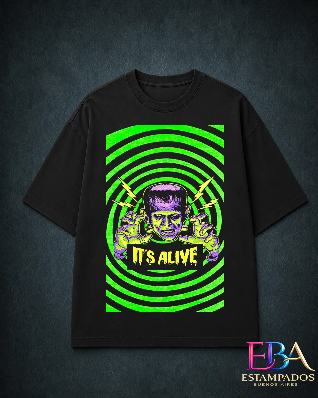 Remera negra con Frankenstein en verde y violeta sobre círculos verdes y la frase It's Alive