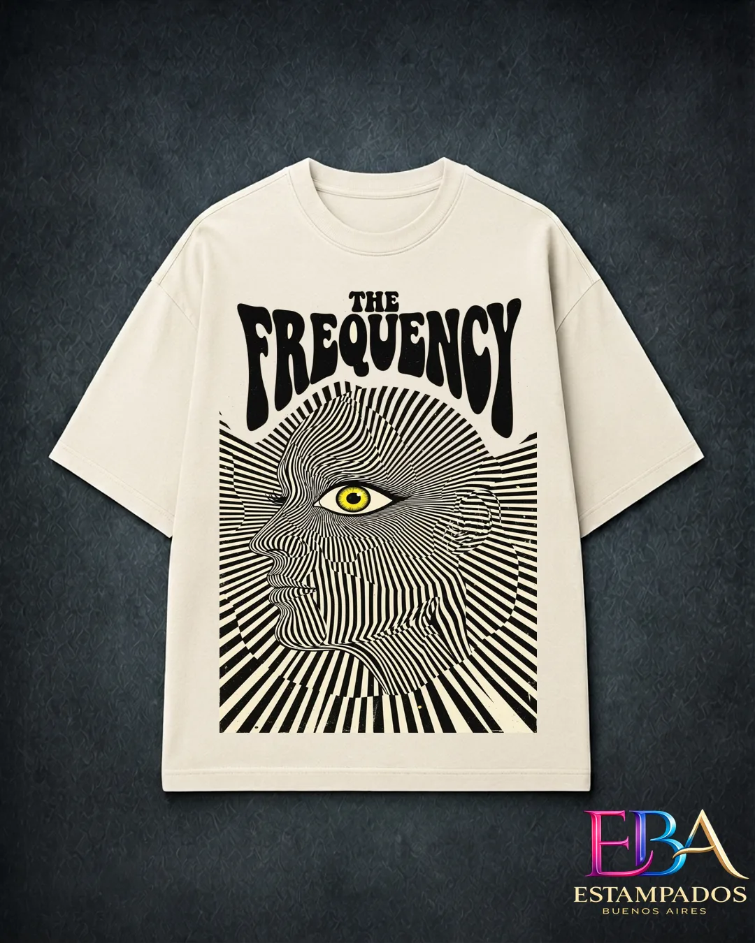 Remera crema con rostro de líneas ópticas en blanco y negro, un ojo amarillo y la frase The Frequency